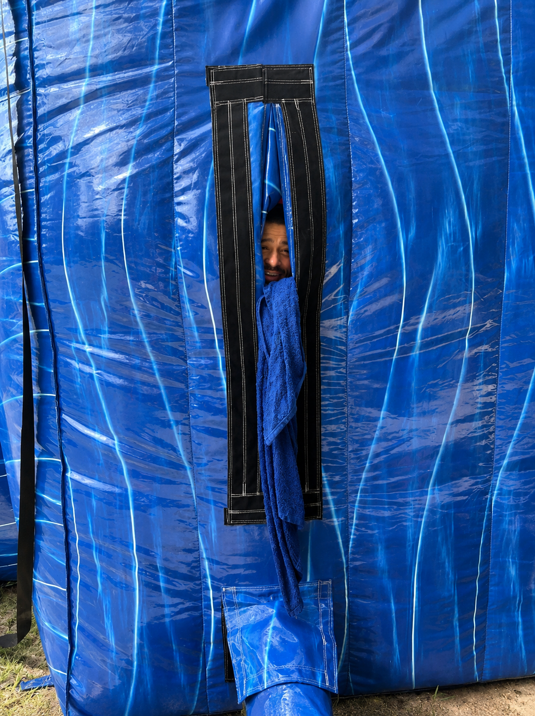 Smiling staff member peeking out from the doorway of a blue inflatable