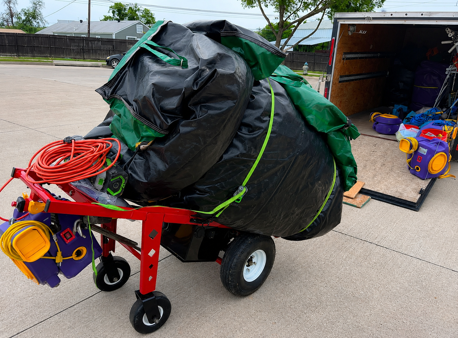 Equipment cart loaded with a wrapped inflatable, blowers, and cords ready for delivery from the trailer