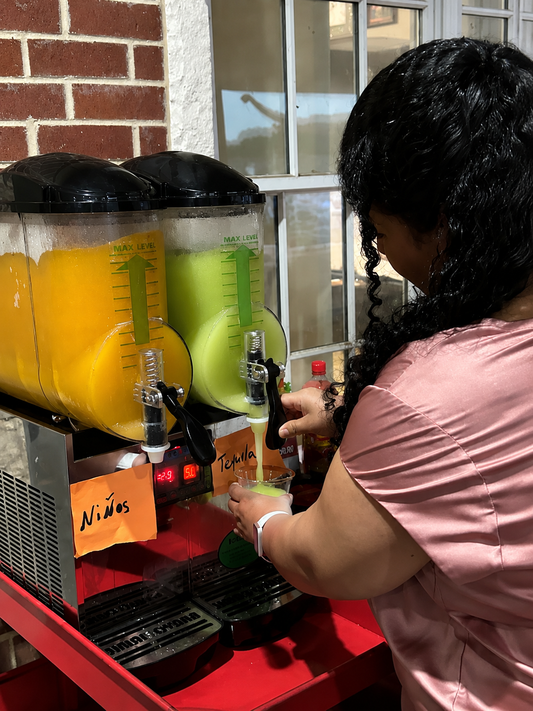 Frozen margarita machine pouring a green frozen drink at an event