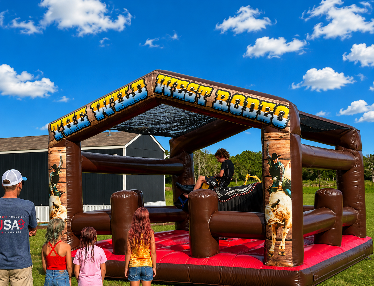 The Wild West Rodeo mechanical bull inflatable with a rider and family watching during the day